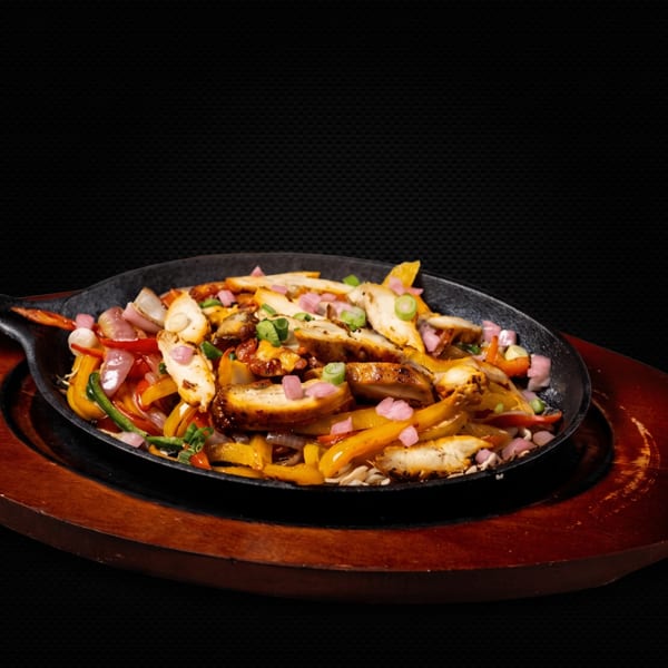 Sizzling chicken fajitas with colorful bell peppers and onions in a cast iron skillet.